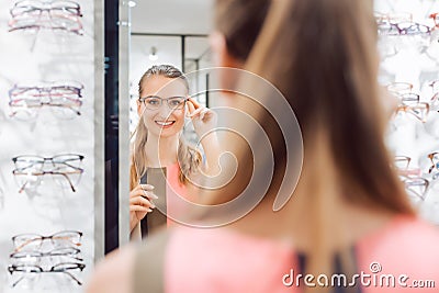 Young woman trying fashionable glasses in optometrist store Stock Photo