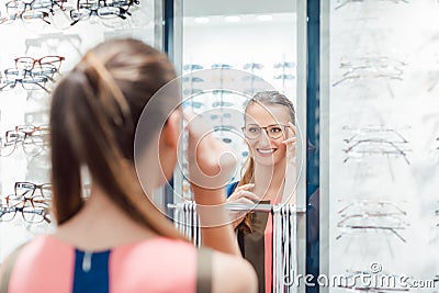 Young woman trying fashionable glasses in optometrist store Stock Photo