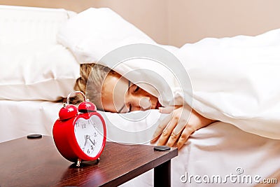 Young woman trying to sleep when alarm clock ringing Stock Photo