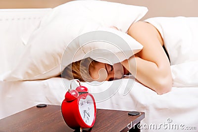 Young woman trying to sleep when alarm clock ringing Stock Photo