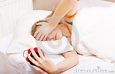 Young woman trying to sleep when alarm clock ringing Stock Photo