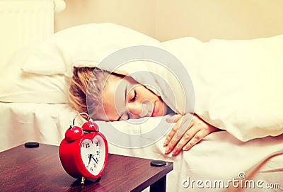 Young woman trying to sleep when alarm clock ringing Stock Photo