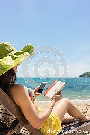 Young woman undecided between reading a book and spending time o Stock Photo