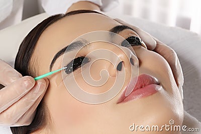Young woman undergoing eyelash lamination and tint in salon, closeup Stock Photo