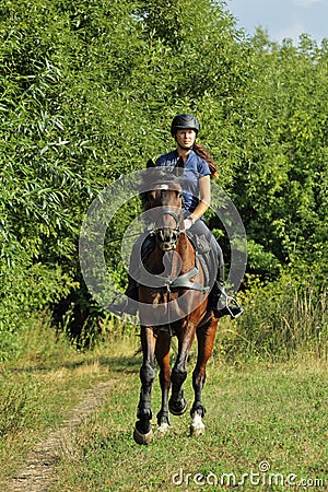 Young woman in uniform and helmet riding horse Stock Photo