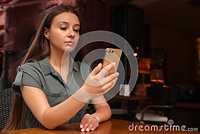 Young woman unlocking smartphone with facial scanner in outdoors cafe. Biometric verification Stock Photo