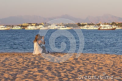 Young woman using camera at the beach Editorial Stock Photo