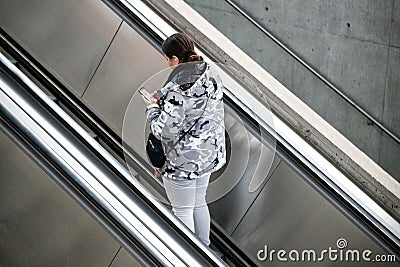 Young woman using cell phone on escalator in shopping mal Editorial Stock Photo