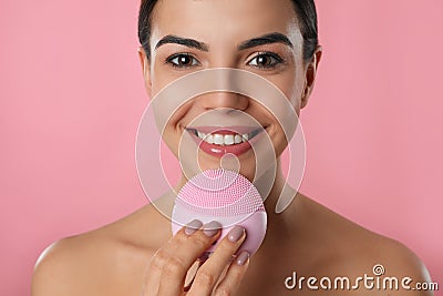 Young woman using facial cleansing brush on background, closeup. Washing accessory Stock Photo