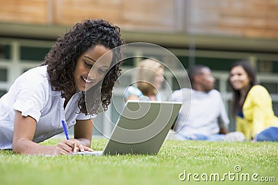 Young woman using laptop on campus lawn Stock Photo