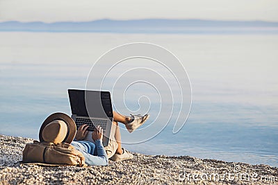 Young woman using laptop computer on a beach. Freelance work concept Stock Photo