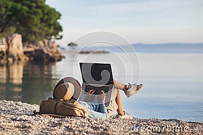 Young woman using laptop computer on a beach. Freelance work concept Stock Photo