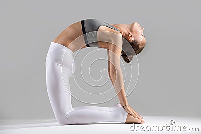 Young woman in Ustrasana pose, grey studio background Stock Photo