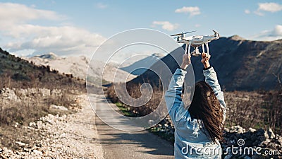 Young woman videographer catching flying aircraft with camera.Controlling landing of drone.Female filmmaker in nature Stock Photo