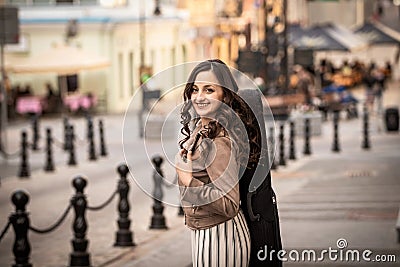 Young woman with a violin case smiling againgt a street Stock Photo