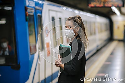 Young woman waits for the subway with a medical mask Stock Photo