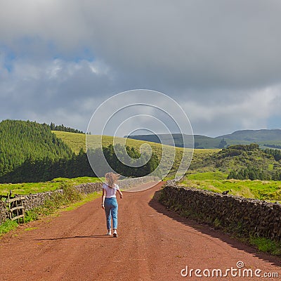 Young woman walk at country road. Fields with blue sky. Terceira Stock Photo