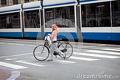Young woman walking across a crosswalk with a bicycle in Amsterdam Netherlands (Holland) Europe Editorial Stock Photo