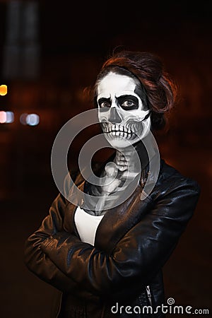 Young woman walking on avenue. Face art for Halloween party. Street portrait. Waist up. Night city background Stock Photo