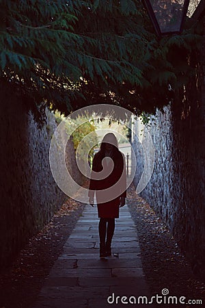 Woman walking away down a dark alley Stock Photo