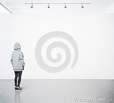 Young woman walking in modern gallery and looking at the blank canvas. Square Stock Photo