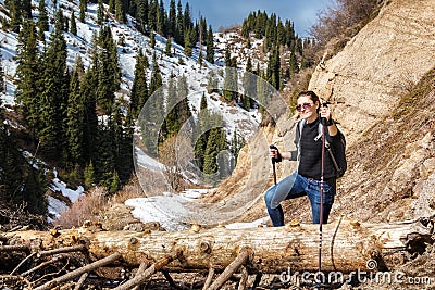 Young woman with walking sticks overcomes an obstacle in mountains Stock Photo