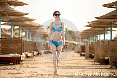 Young woman walking on sunny sand beach Stock Photo