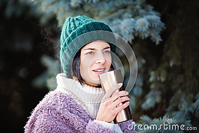 Young woman walking on winter day, holding travel stainless Steel mug with hot coffee. reusable water bottle Stock Photo
