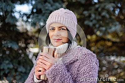 Young woman walking on winter day, holding travel stainless Steel mug with hot coffee. reusable water bottle Stock Photo