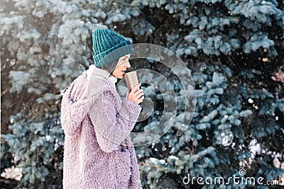 Young woman walking on winter day, holding travel stainless Steel mug with hot coffee. reusable water bottle Stock Photo