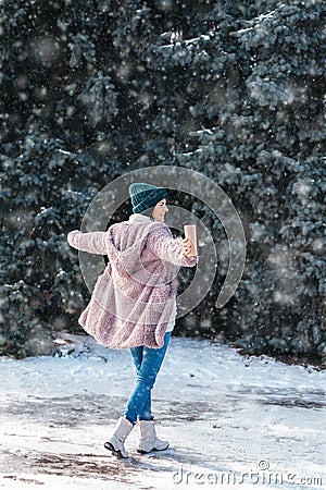 Young woman walking on winter day, holding travel stainless Steel mug with hot coffee. reusable water bottle Stock Photo