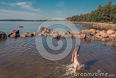 A young woman walks on the water. Lady bathes. Concept of summer vacation, skin and health care, relaxation Stock Photo