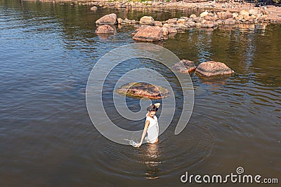 A young woman walks on the water. Lady bathes. Concept of summer vacation, skin and health care, relaxation/ Stock Photo