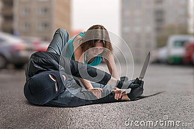 Young woman was attacked by armed thief and is fighting and defending herself. Stock Photo