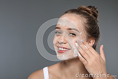 Young woman washing face with soap on grey Stock Photo