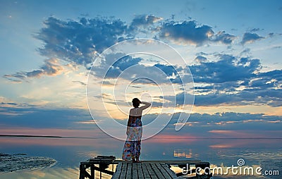 Young woman watching the sunset on sea coast Stock Photo