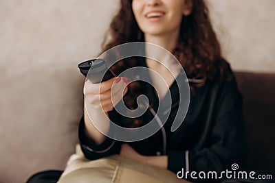 Young woman watching TV in the room while sitting on sofa. View channels. Stock Photo