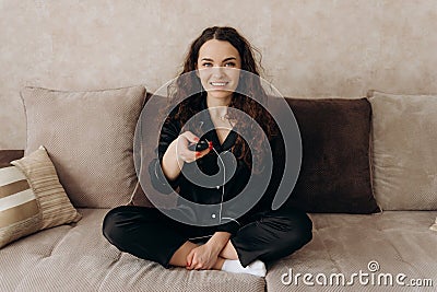 Young woman watching TV in the room while sitting on sofa. View channels. Stock Photo