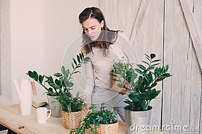 Young woman watering flowerpots at home. Casual lifestyle series in modern scandinavian interior Stock Photo