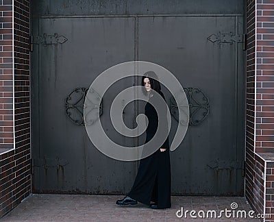 Young woman wearing black clothes posing near gates Stock Photo