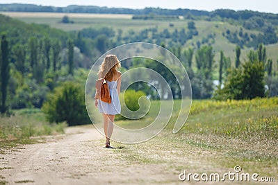 Young woman with a leather backpack on a summer rural road Stock Photo