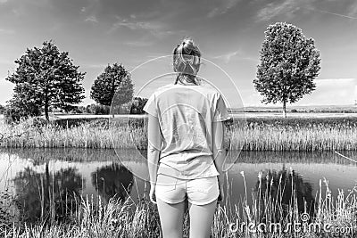 Young woman wearing casual summer clothes enjoying beautiful view of peaceful countryside. Stock Photo