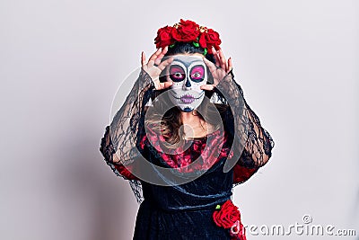 Young woman wearing day of the dead costume over white trying to open eyes with fingers, sleepy and tired for morning fatigue Stock Photo