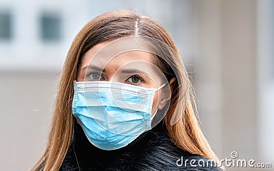 Young woman wearing disposable blue virus face mouth nose mask, closeup portrait. Coronavirus covid-19 outbreak prevention concept Stock Photo