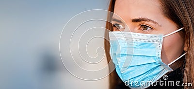 Young woman wearing disposable blue virus face mouth nose mask, closeup portrait - wide banner with space for text left side. Stock Photo