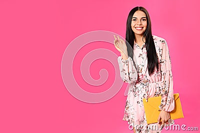 Young woman wearing floral print dress with elegant clutch on background. Space for text Stock Photo