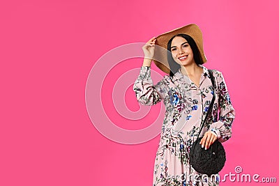 Young woman wearing floral print dress and straw hat on background. Space for text Stock Photo