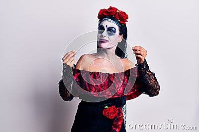 Young woman wearing mexican day of the dead makeup doing money gesture with hands, asking for salary payment, millionaire business Stock Photo