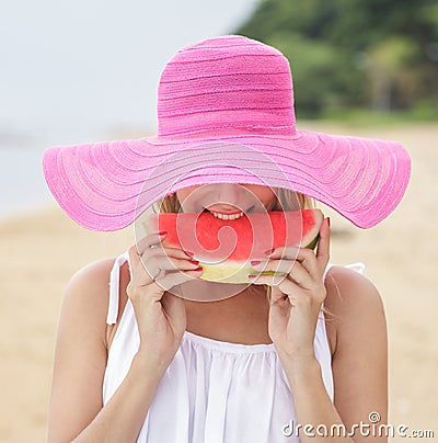 Young woman wearing pink sunhat eating fresh watermelon Stock Photo