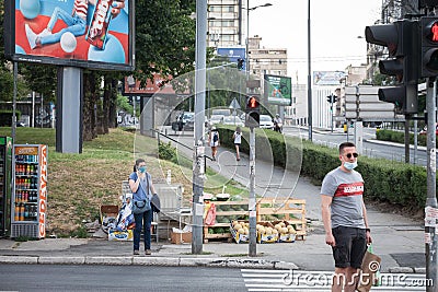 Young woman wearing a respiratory face mask making a phone call on her smartphone apps in the street of Belgrade Editorial Stock Photo